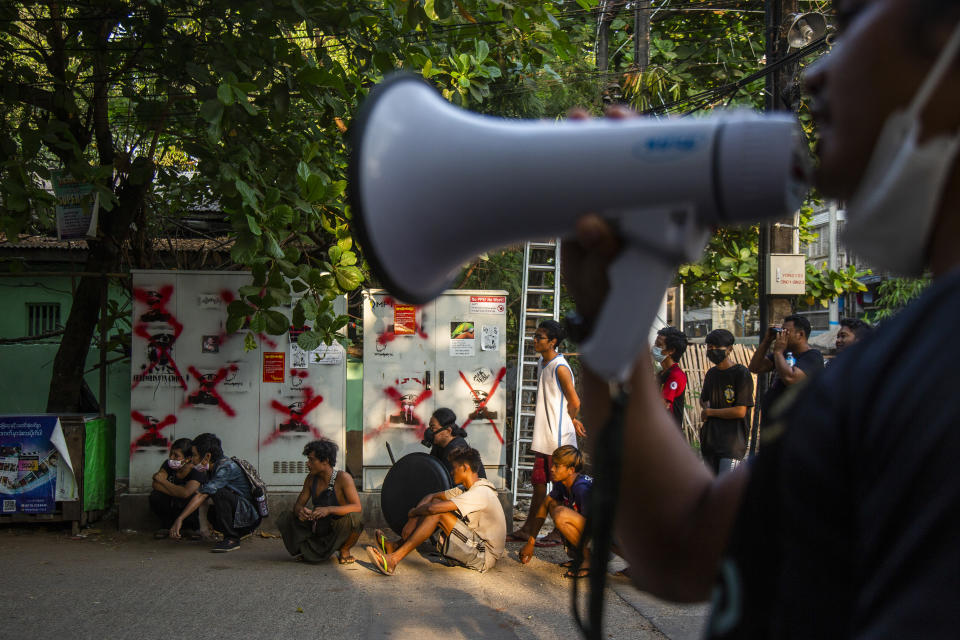 Anti-coup protesters and residents monitor police and military occupying a roadblock in Yangon, Myanmar, Friday, March 19, 2021. The authorities in Myanmar have arrested a spokesman for ousted leader Aung San Suu Kyi's political party as efforts to restrict information about protests against last month's military takeover are tightened. (AP Photos)