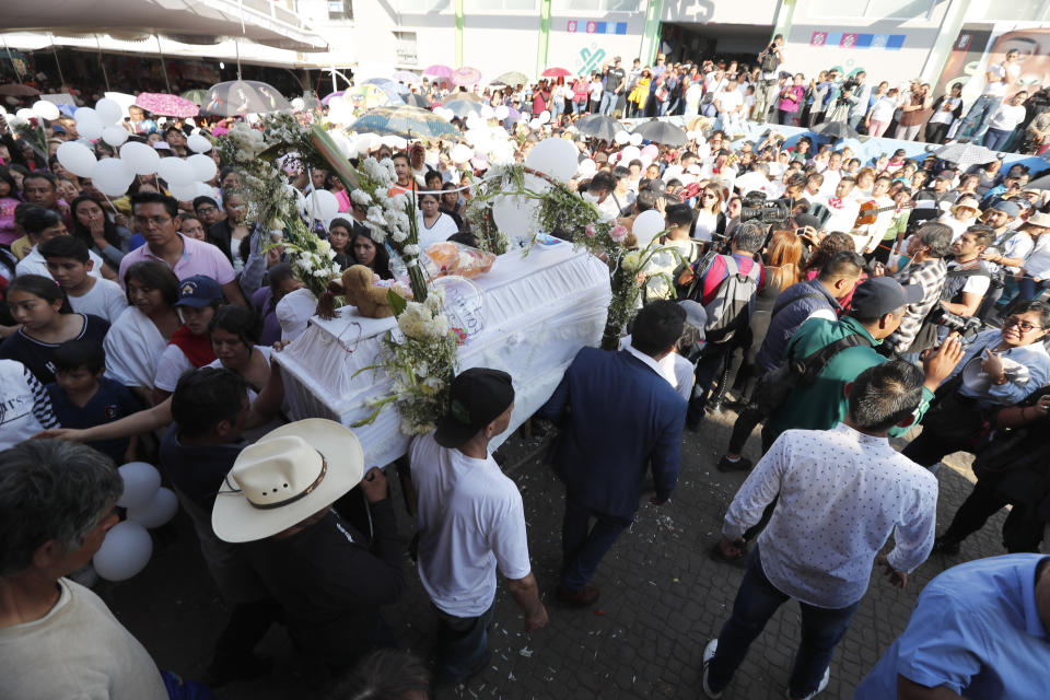 The casket of 7-year-old murder victim Fatima is taken to the gate of the primary school from where she was abducted, as her funeral procession walks to a church for a funeral Mass in Mexico City, Tuesday, Feb. 18, 2020. Fatima's body was found wrapped in a bag and abandoned in a rural area on Saturday. Five people have been questioned in the case, and video footage of her abduction exists. (AP Photo/Marco Ugarte)