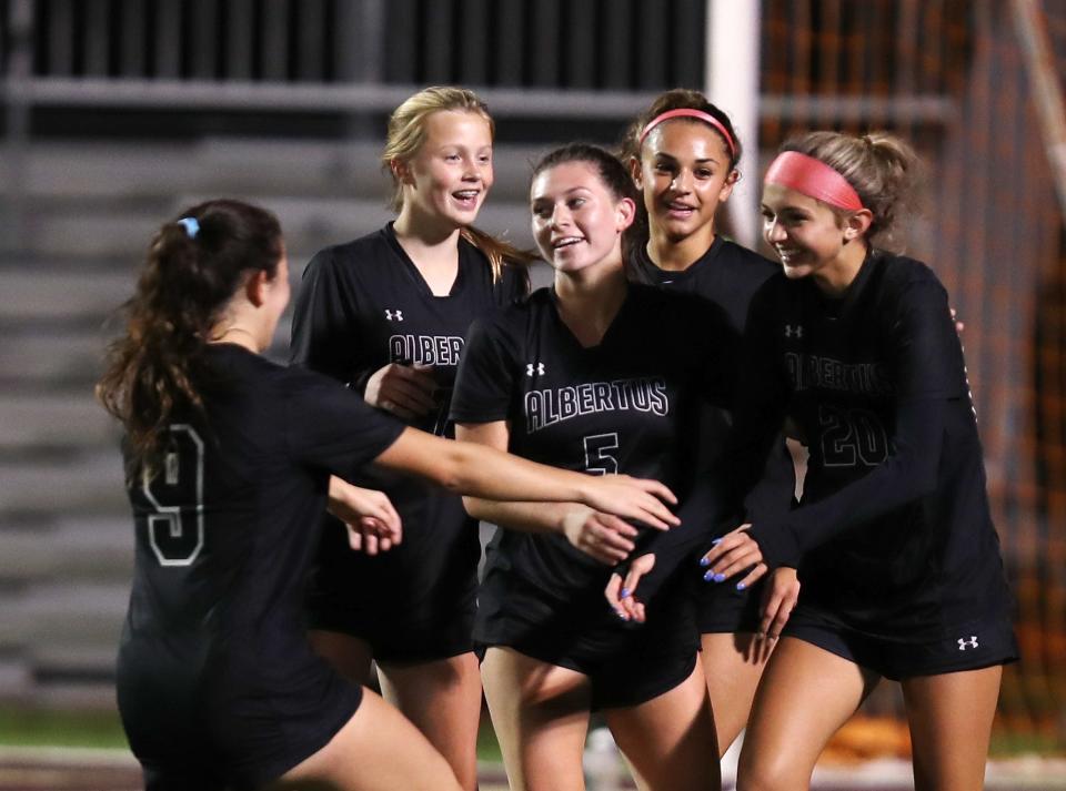 Albertus Magnus' Grace Burns (5, center), Sofia DiPrima (20, right) and Julia Lombardo (9, left) celebrate after a goal against Goshen during the girls soccer Class B state regional semifinals on Nov. 1, 2022.