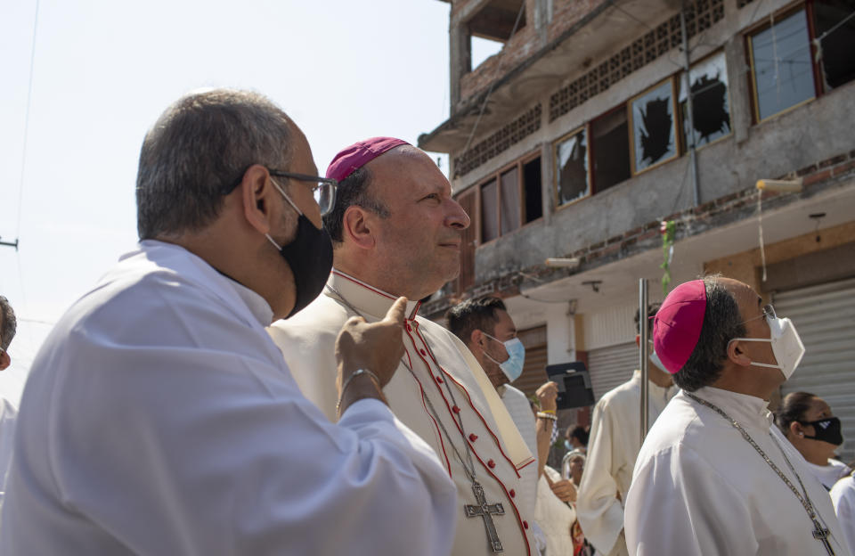 Monsignor Franco Coppola, the Vatican's diplomat to Mexico, looks at broken windows upon arrival to Aguililla, a town that has been cut off by warring cartels in Michoacan state, Mexico, Friday, April 23, 2021, where he will meet families and celebrate Mass. State police and soldiers were sent in to restore order earlier this month, but cartels responded by parking hijacked trucks across roads to block them, as well as digging deep trenches across roadways. (AP Photo/Armando Solis)