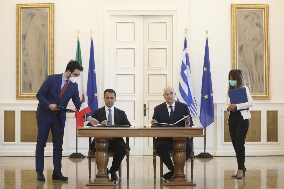 Greek Foreign Minister Nikos Dendias, right, and his Italian counterpart Luigi Di Maio asign an agreement following their meeting , in Athens, on Tuesday, June 9, 2020. Greece will lift all restrictions on Italian tourists entering the country gradually between June 15 and the end of the month, Greece's foreign minister said Tuesday.(Costas Baltas /Pool via AP)