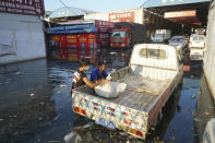 Xing, right, a shop owner at Yubei Agricultural and Aquatic Products World, wraps her goods in a plastic bag at the market in Xinxiang in central China's Henan Province, Monday, July 26, 2021. Record rain in Xinxiang last week left the produce and seafood market soaked in water. Dozens of people died in the floods that immersed large swaths of central China's Henan province in water. (AP Photo/Dake Kang)