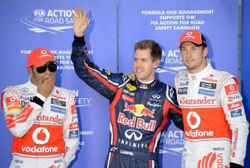 Red Bull-Renault driver Sebastian Vettel of Germany (centre) poses with McLaren-Mercedes British drivers Jenson Button (right) and Lewis Hamilton after a qualifying session during the Formula One Japanese Grand Prix at Suzuka. Vettel became Formula One's youngest back-to-back world champion when he finished third in the Japanese Grand Prix behind Button and Fernando Alonso