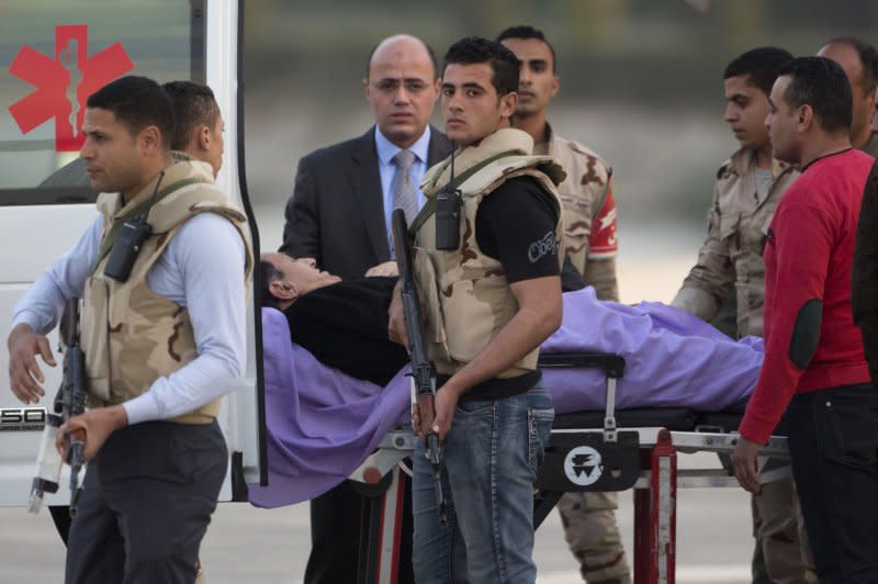 埃及前獨裁者穆巴拉克在維安人員護送下進入救護車。（美聯社）