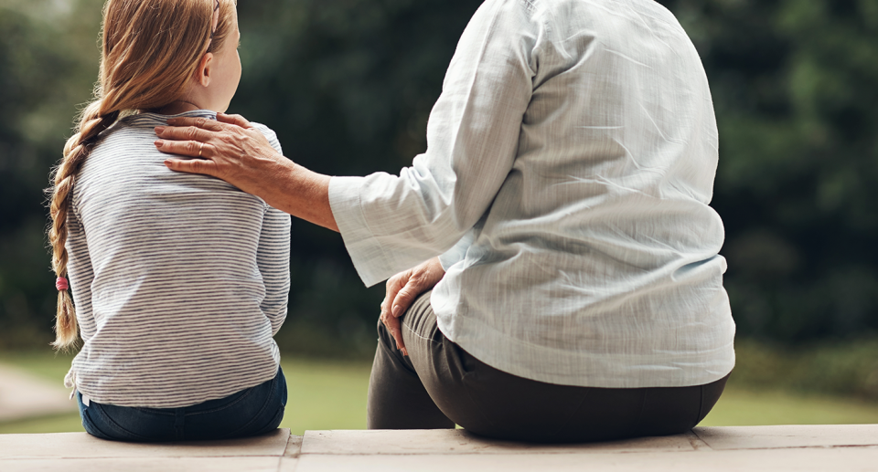 A child is seen beside a parent figure. 