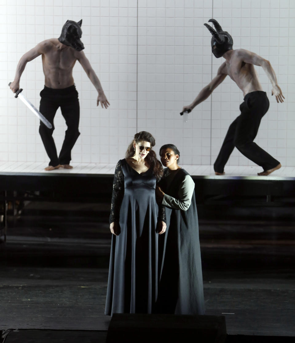 In this picture taken Friday, June 21, 2013, Anja Harteros in the role of Leonora, left, sings during a dress rehearsal for the opera "Il Trovatore" by Giuseppe Verdi in the Bavarian State Opera House in Munich, southern Germany. This wild new production by Olivier Py opened the company's annual Munich Opera Festival. It's a non-stop barrage of nightmarish images mixing styles and periods that assault the audience at lightning speed on a multi-tiered revolving set. (AP Photo/Matthias Schrader)