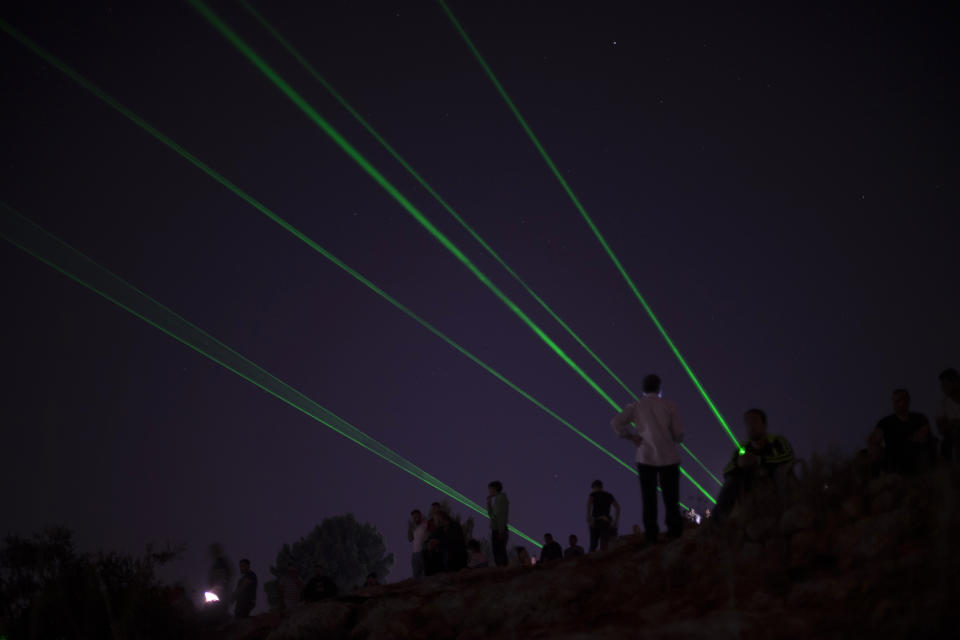 Palestinian demonstrators shine laser torches during a demonstration against the West Bank Jewish settlement outpost of Eviatar that was rapidly established last month, at the Palestinian village of Beita, near the West Bank city of Nablus, Sunday, June 27, 2021. The Palestinians say it was established on their farmland and fear it will grow and merge with other large settlements in the area. (AP Photo/Majdi Mohammed)