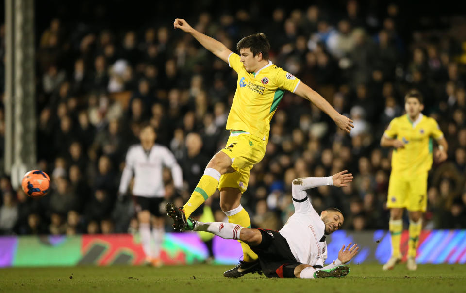 Fulham's Clint Dempsey, falls to the ground as he challenges Sheffield United's Harry Maguire for the ball during their 4th round replay English FA Cup soccer match between Fulham and Sheffield United at Craven Cottage stadium in London, Tuesday, Feb. 4, 2014. (AP Photo/Alastair Grant)