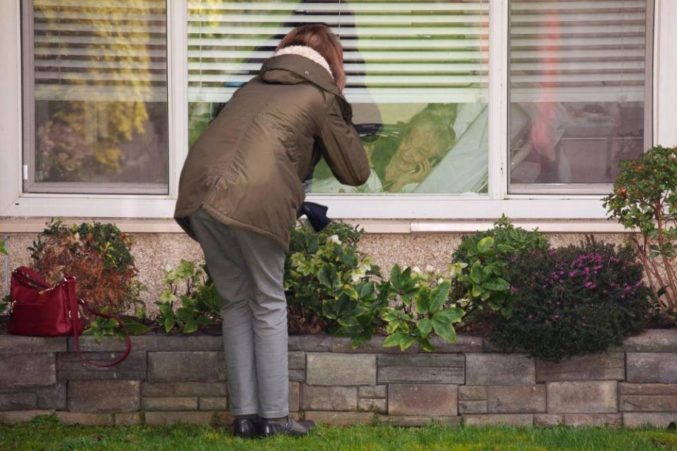 A woman talks on the phone to her mother as they look at each other through a window at the Life Care Center of Kirkland in Washington on 8 March.