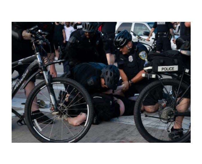 Milwaukee police officers hold down Cameron Murdoch with a knee to his neck area.