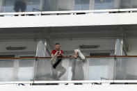 Passengers talk at each other on the MS Westerdam, owned by Holland America Line, docked at the port of Sihanoukville, Cambodia, Friday, Feb. 14, 2020. Hundreds of cruise ship passengers long stranded at sea by virus fears cheered as they finally disembarked Friday and were welcomed to Cambodia. (AP Photo/Heng Sinith)