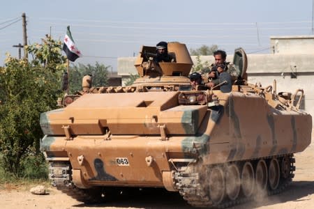 Turkey-backed Syrian rebel fighters ride on a military truck near the border town of Tel Abyad