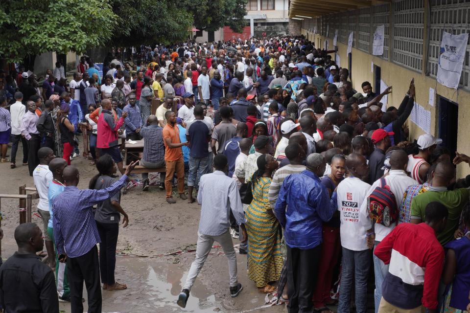 Hundreds of Congolese voters who have been waiting at the St. Raphael school in the Limete district of Kinshasa Sunday Dec. 30, 2018, storm the polling stations after the voters listings were finally posted five hours after the official start of voting. Forty million voters are registered for a presidential race plagued by years of delay and persistent rumors of lack of preparation. (AP Photo/Jerome Delay)