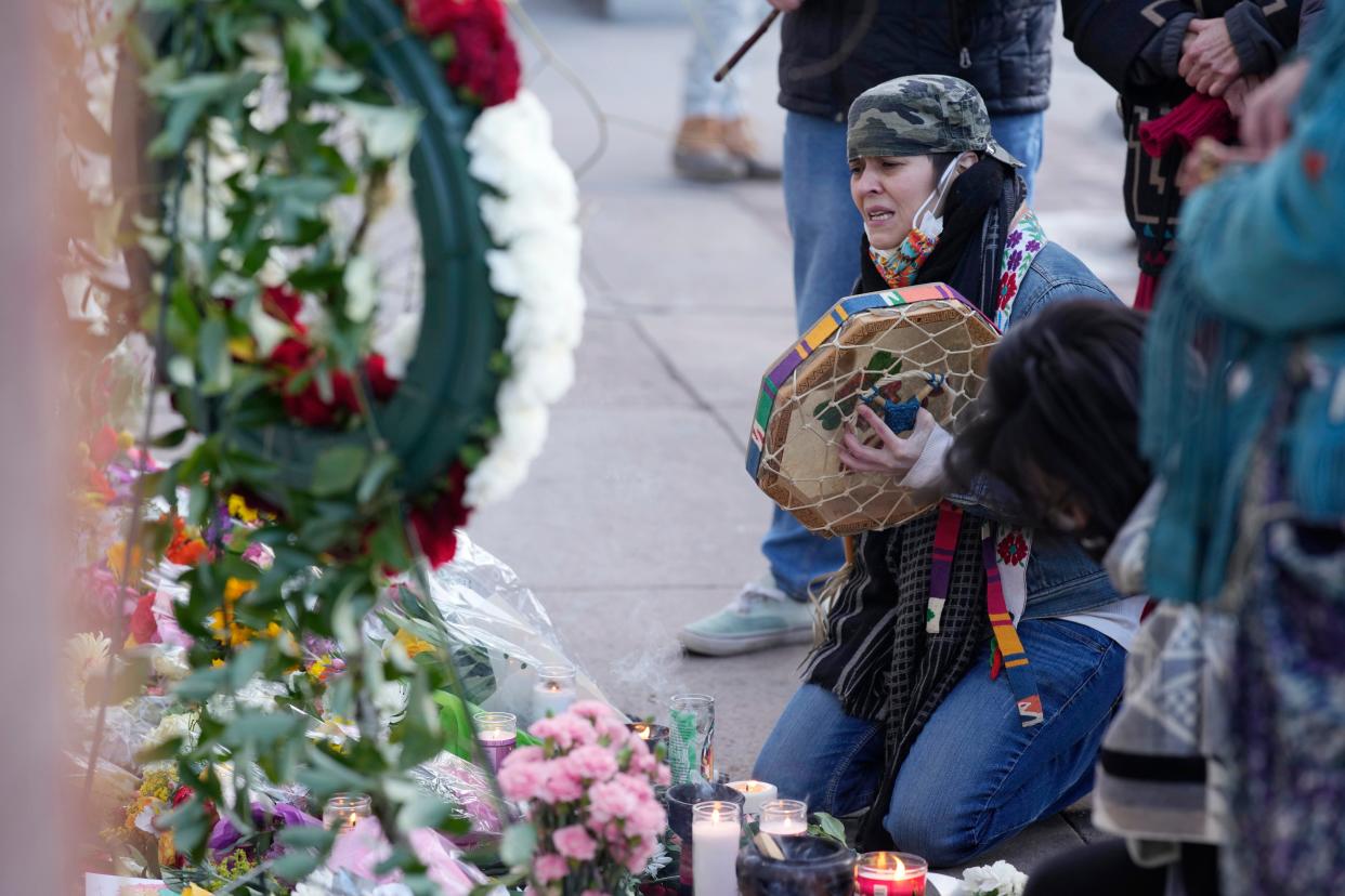 Mourners gather outside the door of a tattoo parlor along South Broadway Tuesday, Dec. 28, 2021, in Denver, one of the scenes of a shooting spree that left multiple people dead, including the suspected shooter Monday evening, and a few more people wounded.