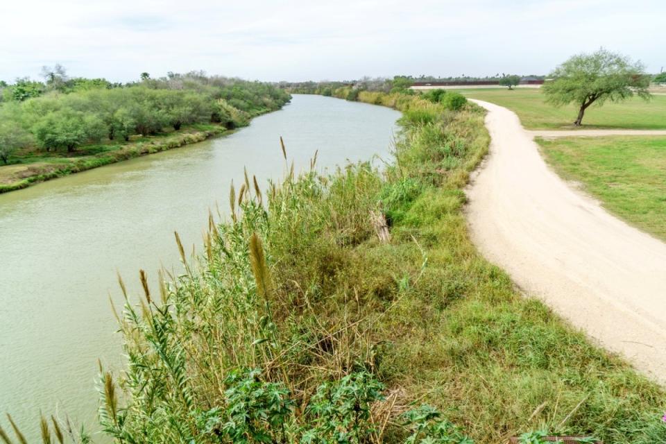 Grassy landscape with walkway along river.