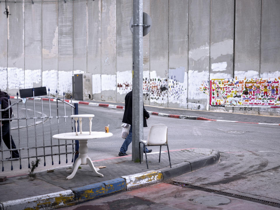 FILE - Palestinians walk by a section of the Israeli separation barrier in the West Bank village of Abu Dis on the outskirts of Jerusalem, Jan. 31, 2022. (AP Photo/Oded Balilty, File)