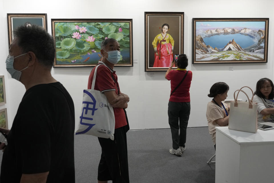 Visitors to the Beijing Art Exposition pass by a booth displaying North Korean paintings run by The Paintings Say Arirang gallery that trumpets itself as China's premier seller of North Korean art, in Beijing Sept. 8, 2023. The gallery's existence and conspicuous sales tactics, experts say, highlight China's lax enforcement of U.N. sanctions targeting North Korea to stymie Pyongyang's nuclear program. (AP Photo/Ng Han Guan)