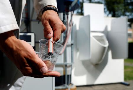 Belgian scientist Sebastiaan Derese pours water from a machine that turns urine into drinkable water and fertilizer using solar energy, at the University of Ghent, Belgium, July 26, 2016. REUTERS/Francois Lenoir