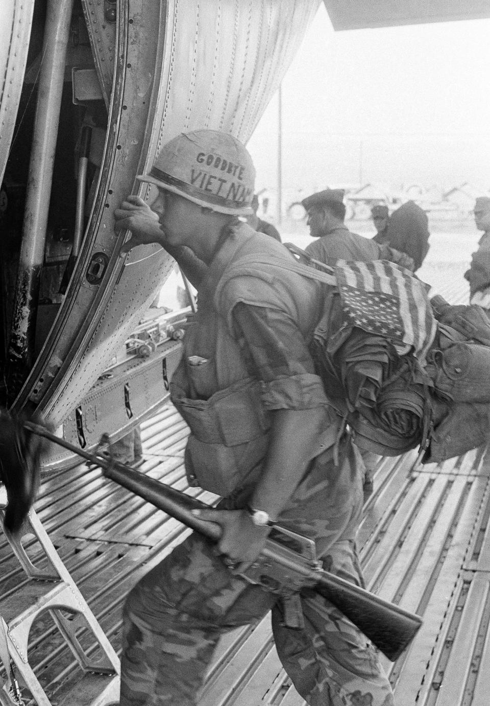 A U.S. Marine with rifle, American flag on his pack and an inscription &quot;Goodbye Vietnam&quot; on his helmet, boards an Okinawa-bound transport plane at Quang Tri, South Vietnam, July 10, 1969.  He was one of 120 men of the 9th Marine Regiment which left Vietnam, and the first Marine contingent to be withdrawn from the war-torn country.