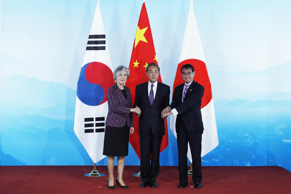 Chinese Foreign Minister Wang Yi, center, holds hands of his South Korean counterpart Kang Kyung-wha, left, and Japanese counterpart Taro Kono ahead of their trilateral meeting at Gubei Town in Beijing Wednesday Aug. 21, 2019. (Wu Hong/Pool Photo via AP)