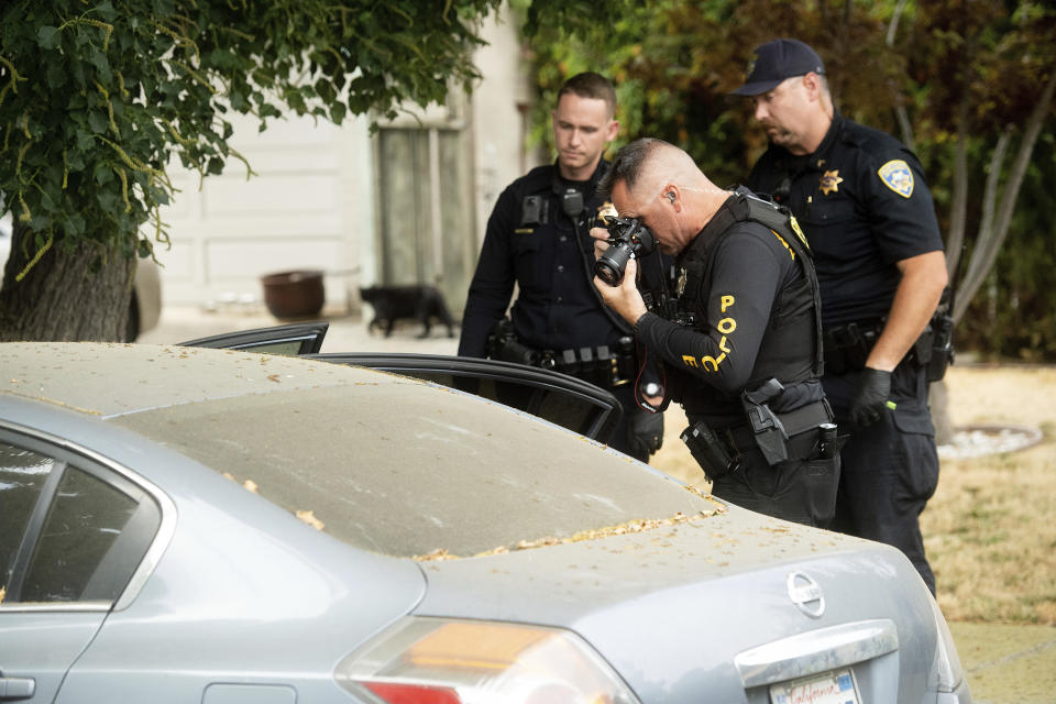 A police officer photographs a car outside the family home of Gilroy Garlic Festival gunman Santino William Legan on Monday, July, 29, 2019, in Gilroy, Calif. The Sunday evening shooting left at least three people, including a 6-year-old boy, dead and wounding about 15 others. (AP Photo/Noah Berger)