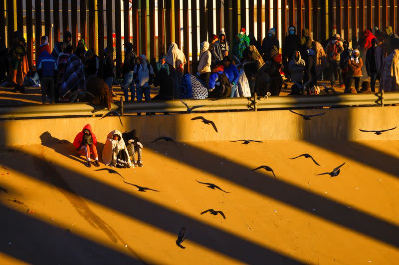 Migrants queue near the border fence after crossing the Rio Bravo river, in Ciudad Juarez