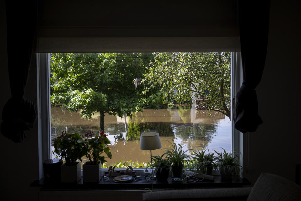 A view of a flooded street from a home in the town of Brommelen, Netherlands, Saturday, July 17, 2021. In the southern Dutch province of Limburg, which also has been hit hard by flooding, troops piled sandbags to strengthen a 1.1-kilometer (0.7 mile) stretch of dike along the Maas River, and police helped evacuate low-lying neighborhoods. (AP Photo/Bram Janssen)