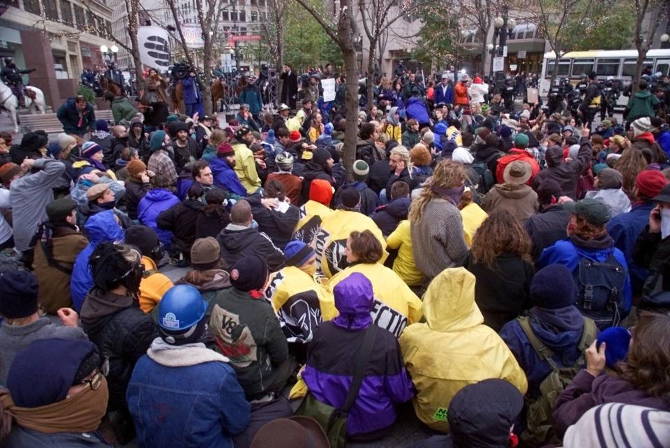 FILE - In this Dec. 1, 1999, file photo, World Trade Organization demonstrators sit peacefully in Westlake Center in downtown Seattle after being arrested by police. Saturday, Nov. 30, 2019 marks 20 years since tens of thousands of protesters converged on Seattle and disrupted a major meeting of the World Trade Organization. The protesters’ message was amplified not just by their vast numbers but by the response of overwhelmed police, who fired tear gas and plastic bullets and arrested nearly 600 people. Two decades later, many of their causes are still relevant. (AP Photo/Beth A. Keiser, File)