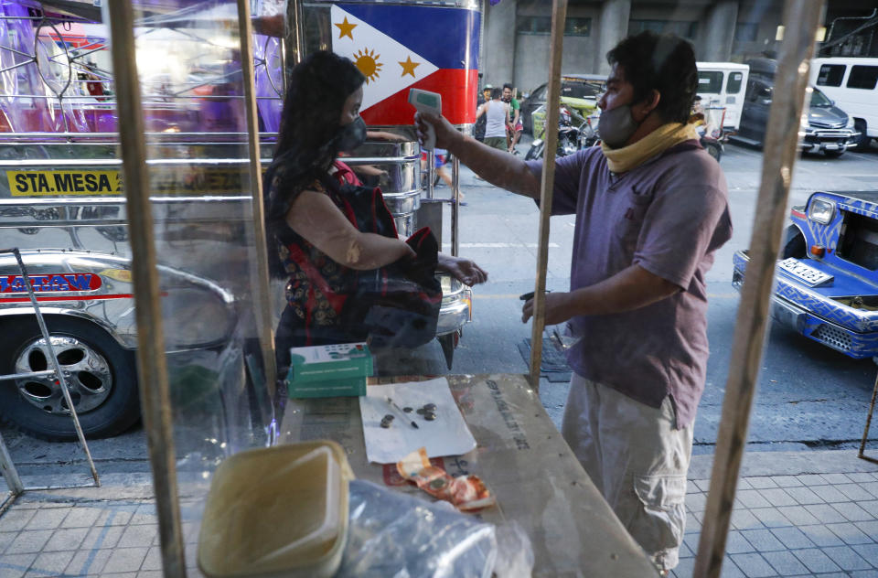 A passenger has her temperature checked to prevent the spread of the new coronavirus as some routes for the Traditional Jeepney buses were opened to help public transportation while the government slowly eases lockdown in metropolitan Manila, Philippines on Friday, July 3, 2020. (AP Photo/Aaron Favila)