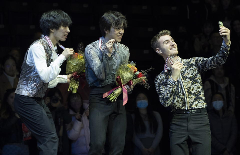Men's bronze medalist Matteo Rizzo of Italy takes a picture of gold medalist Shoma Uno of Japan, center, and silver medalist Kao Miura of Japan during victory ceremonies at the Skate Canada International figure skating competition in Mississauga, Ontario, on Saturday, Oct. 29, 2022. (Paul Chiasson/The Canadian Press via AP)
