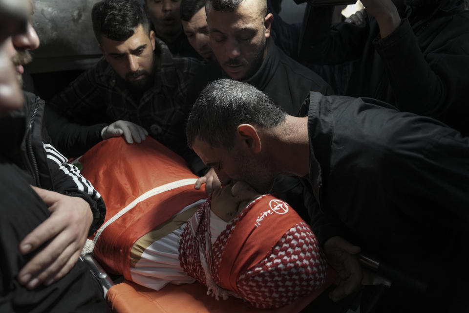 Mourners gather around the body of 14-year-old Palestinian Omar Khumour during his funeral in the West Bank city of Bethlehem, Monday, Jan. 16, 2023. The Palestinian Health Ministry said Khumour died after being struck in the head by a bullet during an Israeli military raid into Dheisha refugee camp near the city of Bethlehem. The Israeli army said that forces entered the Dheisha camp and were bombarded by Molotov cocktails and rocks. It said soldiers responded to the onslaught with live fire. (AP Photo/Mahmoud Illean)