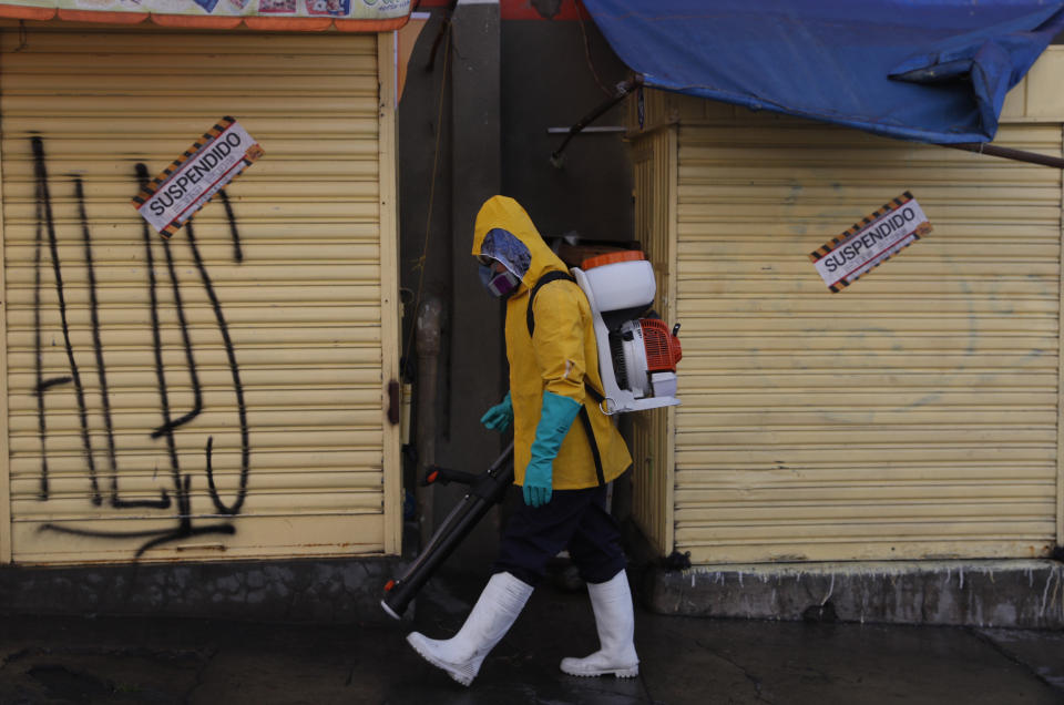 A city worker in full protective gear amid the new coronavirus pandemic disinfects the sidewalk outside the Haiti market in La Paz, Bolivia, Tuesday, June 23, 2020. Health authorities say that a butcher at the marker died several weeks ago of COVID related symptoms, prompting its closure. (AP Photo/Juan Karita)