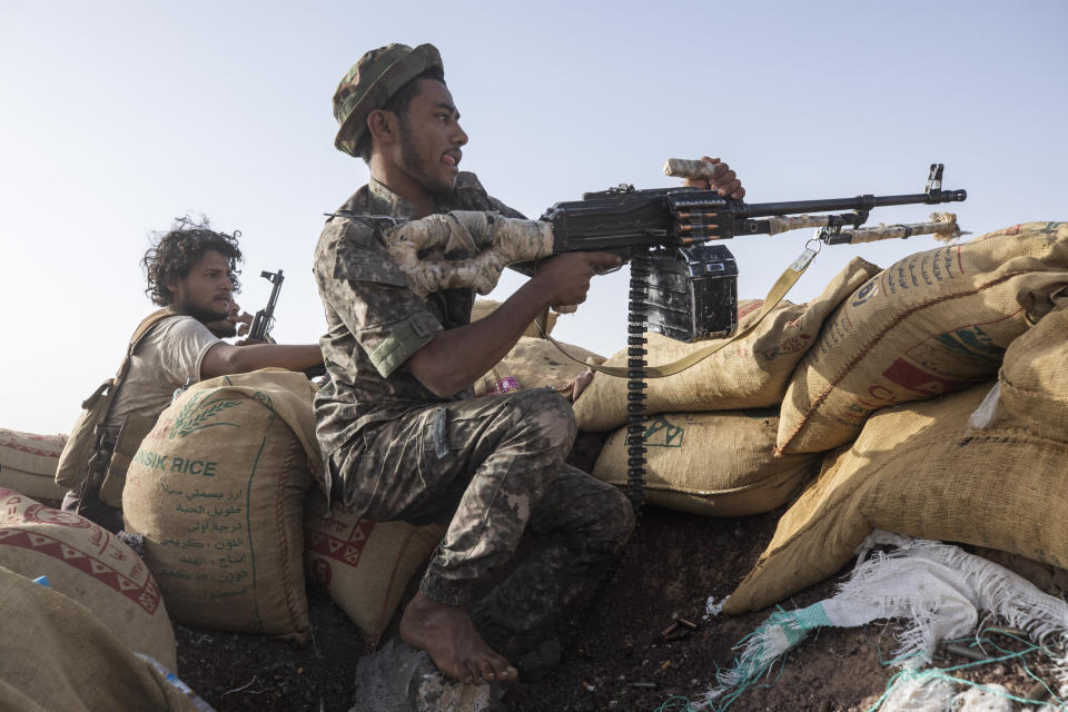 Yemeni fighter Hassan Saleh, left, identifies a target for a fighter during clashes with Houthi rebels on the Kassara front line near Marib, Yemen, Sunday, June 20, 2021. On the most active front line in Yemen's long civil war, the months-long battle for the city of Marib has become a dragged-out grind with a steady stream of dead and wounded from both sides. (AP Photo/Nariman El-Mofty)