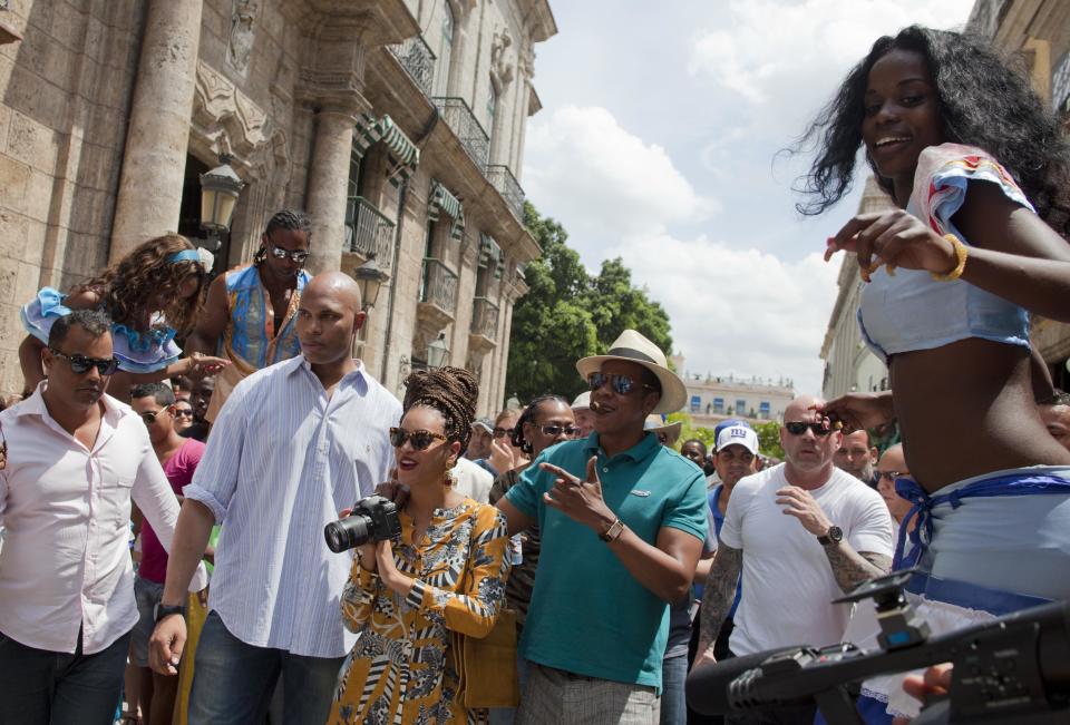 U.S. singer Beyonce and her husband, rapper Jay-Z, are surrounded by body guards as they tour Old Havana where a street performer on stilts looks on, right, in Cuba, Thursday, April 4, 2013. R&B's power couple is in Havana on their fifth wedding anniversary. (AP Photo/Ramon Espinosa)