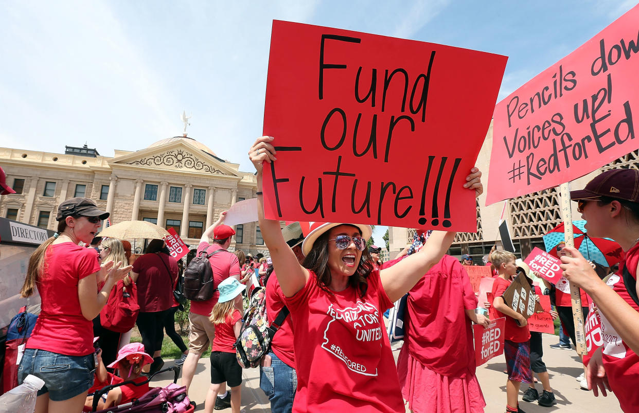 An Arizona teacher holds up a sign in front of the state Capitol during a rally on April 26. Legislation signed by the governor Thursday meets some of their demands. (Photo: Ralph Freso via Getty Images)