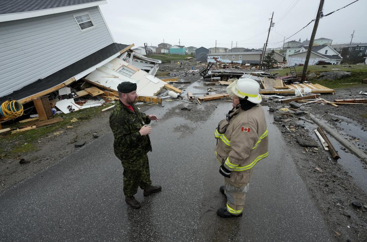 An army officer speaks with a firefighter amidst destroyed homes in Channel-Port aux Basques, N.L., on Sept. 26, 2022. THE CANADIAN PRESS/Frank Gunn