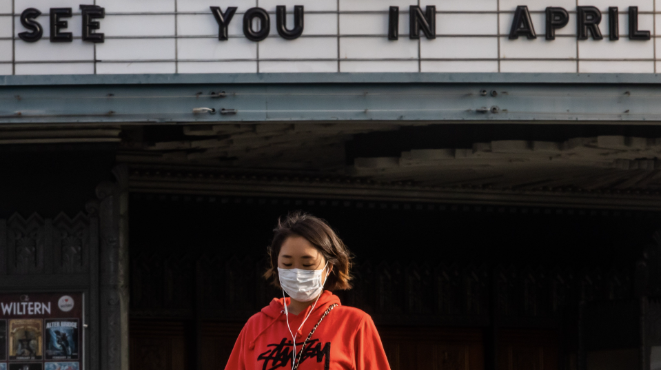 A woman walks wearing a mask to protect herself from the novel coronavirus (COVID-19) in front of a closed theater in Koreatown, Los Angeles, on March 21, 2020 (Photo: APU GOMES/AFP via Getty Images)