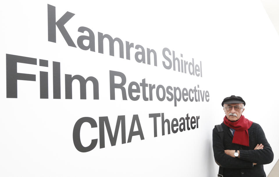 Iranian filmmaker Kamran Shirdel poses beside the sign pointing to where some of his films can be seen at the Carnegie Museum of Art Thursday, Feb. 20, 2014, during his first visit to the U.S. Shirdel began making gritty films of taboo subjects in the 1960s. (AP Photo/Keith Srakocic)