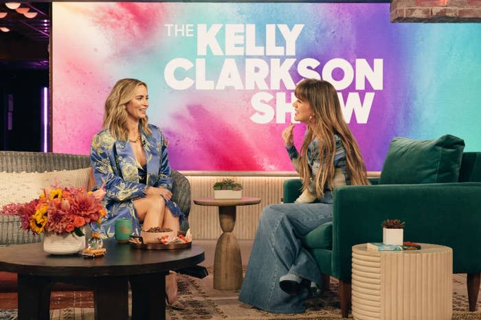 Two guests sit for an interview on "The Kelly Clarkson Show," one wearing a floral dress and the other in denim