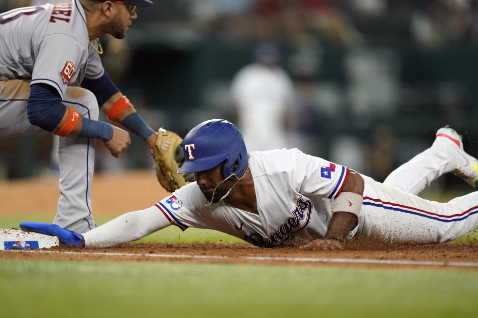 Texas Rangers' Ezequiel Duran, right, dives back to first base, beating the pickoff tag by Houston Astros first baseman Yuli Gurriel during the fourth inning of a baseball game in Arlington, Texas, Tuesday, June 14, 2022. (AP Photo/LM Otero)