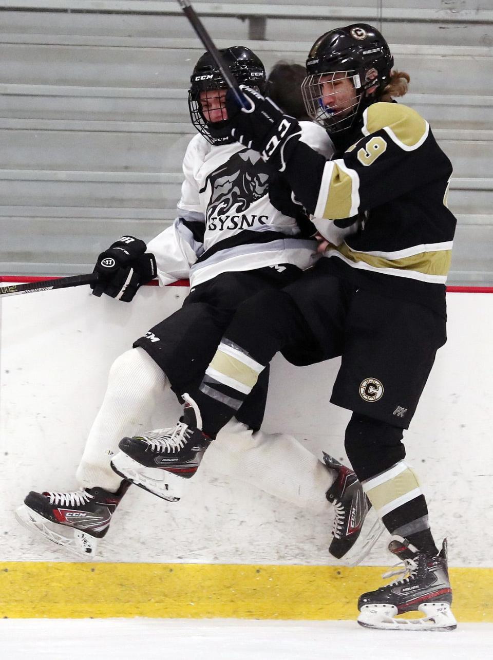 From right, Clarkstown's Matthew Doherty (19) checks the BYSNS's Dylan Filmer (77) into the boards during hockey action at the Brewster Ice Arena Jan. 15, 2022.