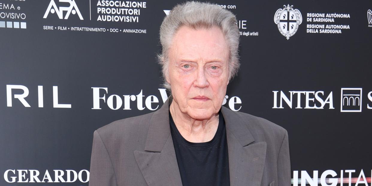 christopher walken wearing a taupe jacket over black top and trousers as he poses on the red carpet