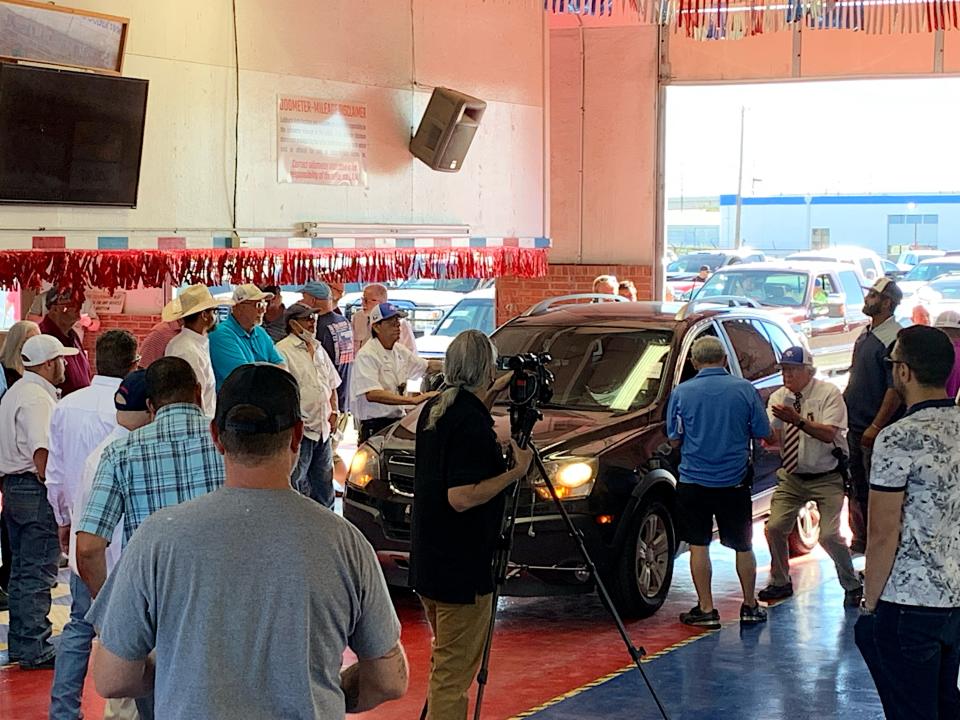 Lubbock Auto Auction 75th Anniversary Sale in 2021. The man with bent knees and hat is Charles Furr.