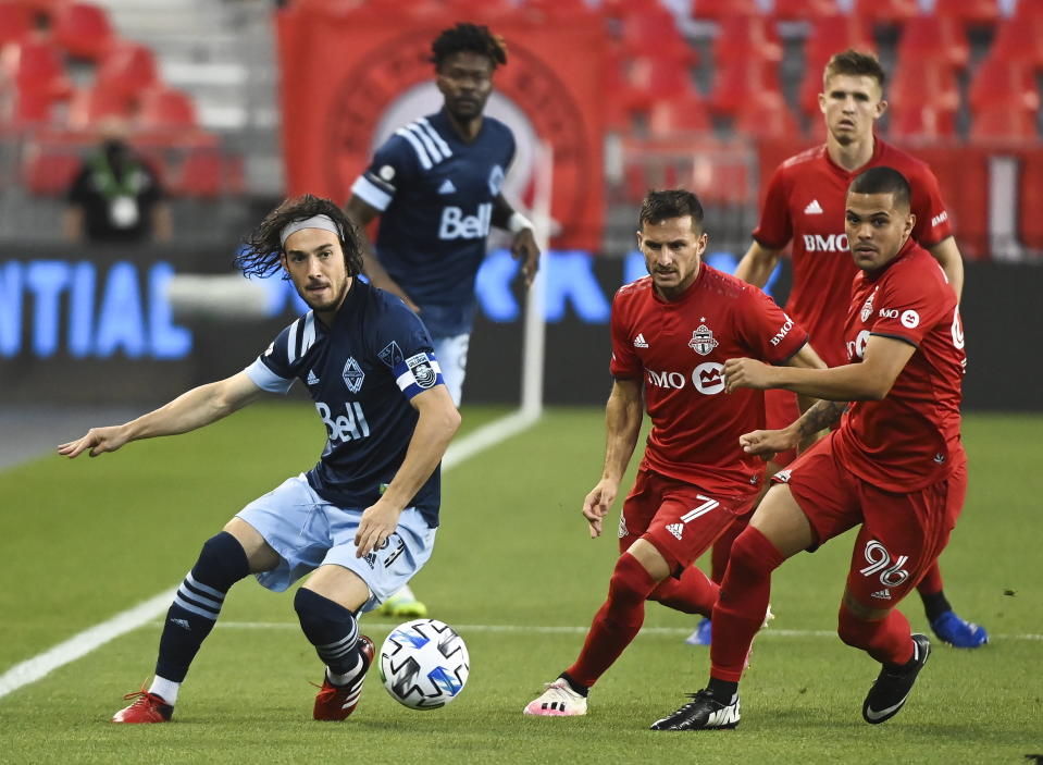 Vancouver Whitecaps midfielder Russell Teibert (31) chased down the ball against Toronto FC forward Pablo Piatti (7) and defender Auro (96) during the first half of an MLS Canadian Championship soccer game in Toronto on Friday, Aug. 21, 2020. (Nathan Denette/The Canadian Press via AP)