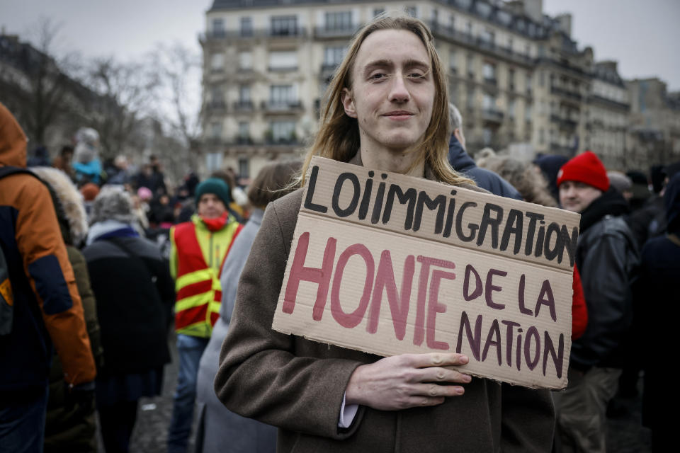 An opponent of France's immigration law holds a placard that reads, "immigration law shame to the nation" during a protest in Paris, Sunday, Jan. 21, 2024. The Constitutional Council is reviewing next week the government's controversial immigration law , to check that measures is in line with the Constitution. (AP Photo/Thomas Padilla)