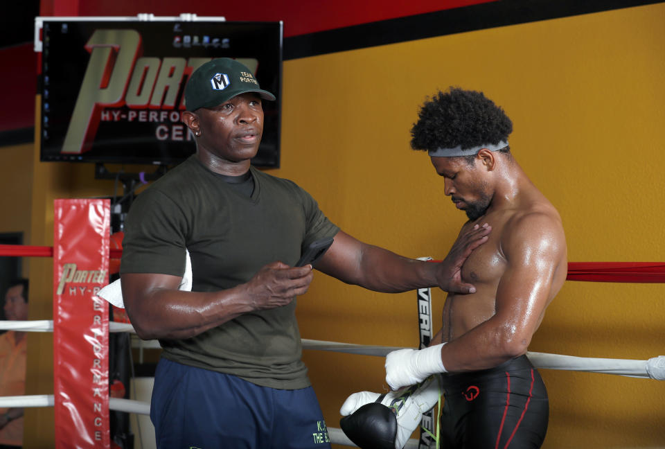 FILE - In this Aug. 15, 2018, file photo, father and trainer Kenny Porter checks the heart rate of welterweight boxer Shawn Porter after a workout in Las Vegas. Shawn Porter needed a place to train, and someone to fight. His father, Kenny, gave him both during the pandemic lockdown. (Steve Marcus/Las Vegas Sun via AP, File)