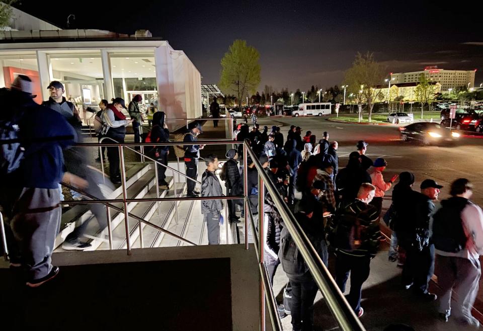 Tesla workers coming off the night shift wait to board buses at the company's Fremont, Calif., factory.