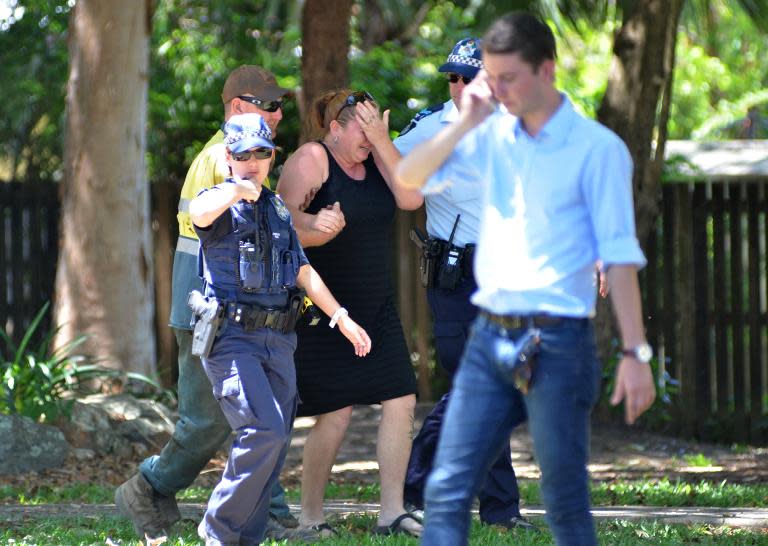 Police comfort a distressed woman at the scene where eight children aged between 18 months and 15 years were found dead at a home in the northern Australian city of Cairns, police said on December 19, 2014