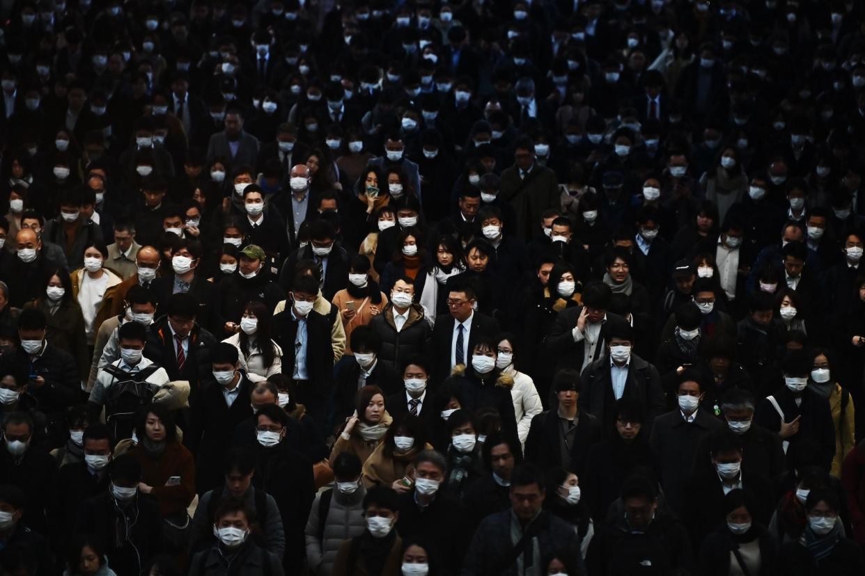 Mask-clad commuters make their way to work during morning rush hour at the Shinagawa train station in Tokyo on February 28, 2020: CHARLY TRIBALLEAU/AFP via Getty Images