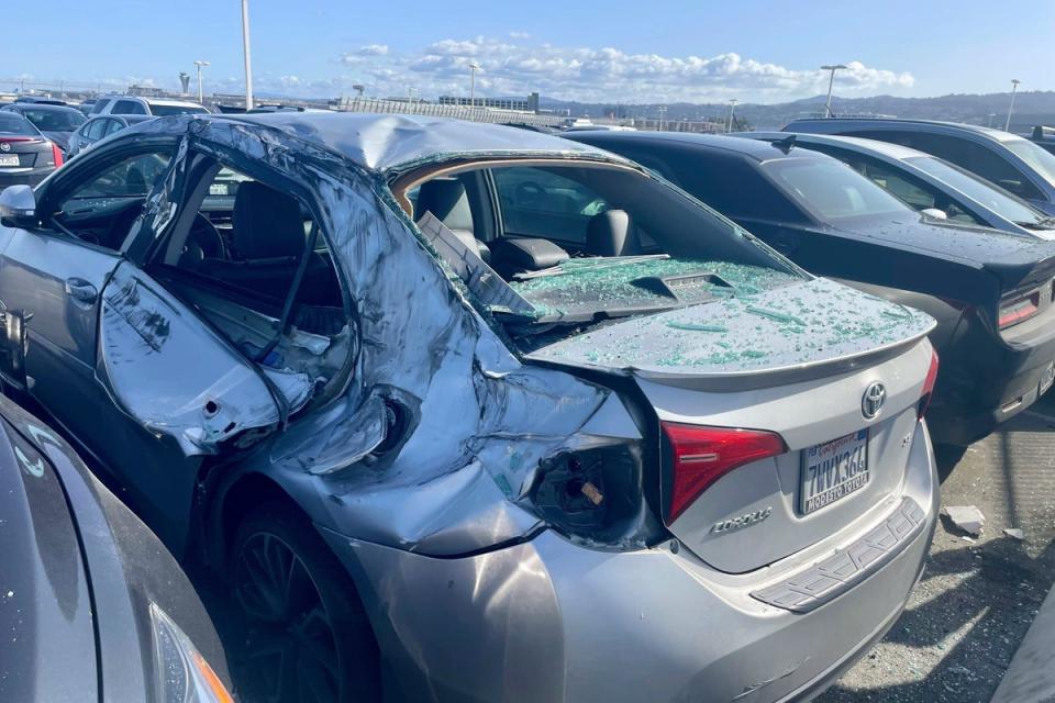 A damaged car is seen in an on-airport employee parking lot after tire debris from a Boeing 777 landed on it at San Francisco International Airport (Copyright 2024 The Associated Press. All rights reserved)